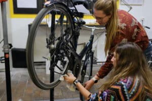 Two women repairing a bike together.