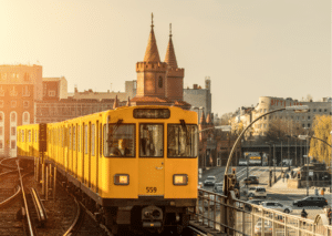 The image shows a yellow tram on high tracks above Berlin